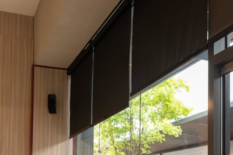 A window with black blinds and a tree outside